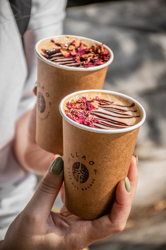 Two artisan coffee cups with floral garnish in sunlight, perfect for outdoor indulgence.